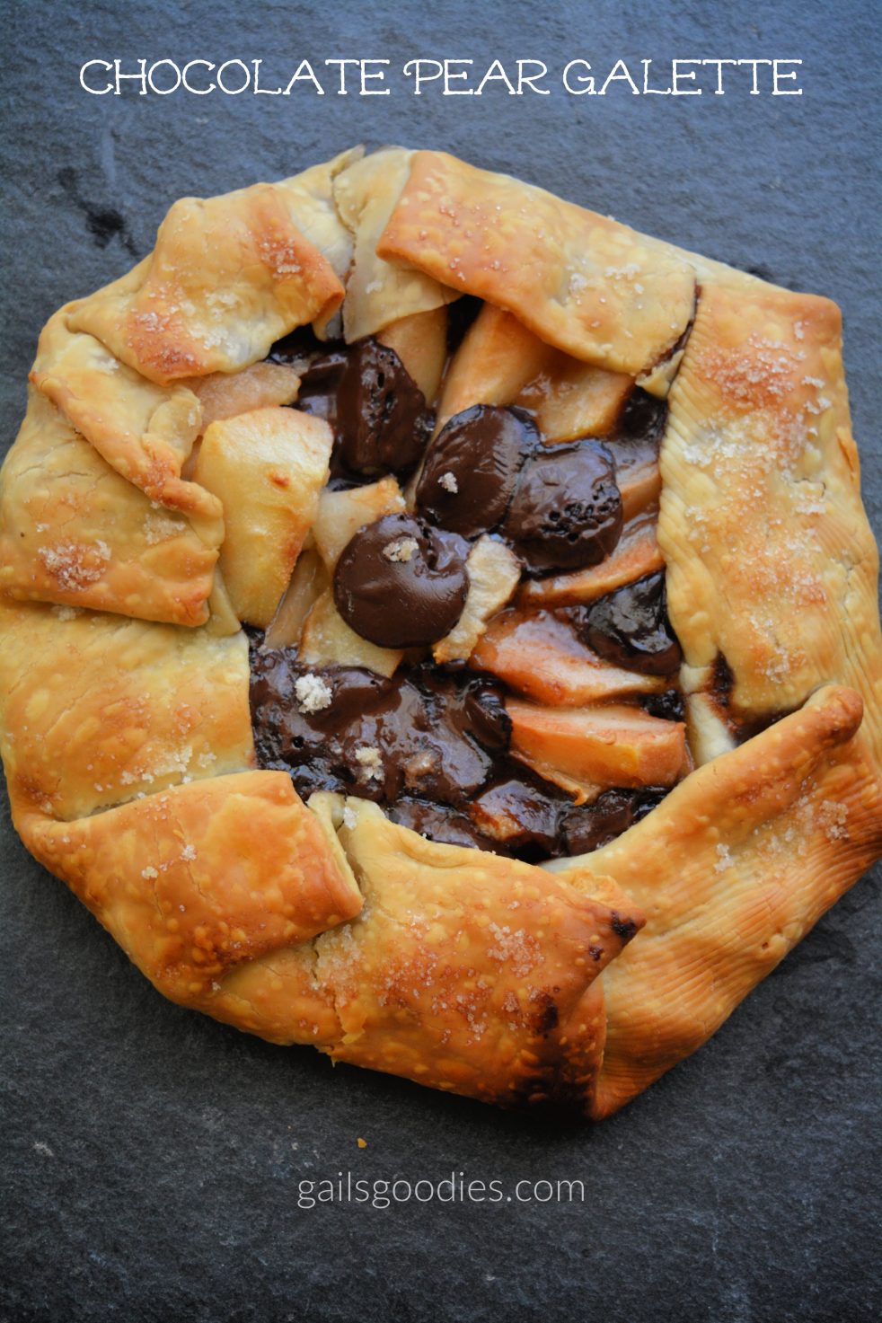 Chocolate pear galetted viewed from the top. The golden pastry is folded up around the sides making a border around the filling. The center is open revealing slices of pear and disks of dark chocolate. The words "Chocolate Pear Galette" are at the top of the photo.
