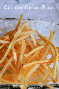 Candied Citrus peel in a hammered glass dish. The peel is cut into thin strips that are dark orange on one side and pale yellow on the other. The words "candied citrus peel" are at the top of the photo.