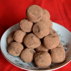 A small dessert plate with a large pyramid of dark chocolate truffles. The cocoa powder coating makes them look a little fuzzy and hides the dark chocolate ganache beneath.