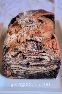 A loaf of chocolate babka with the end sliced off. The bread is intricately swirled with thin layers of chocolate and yeast bread.