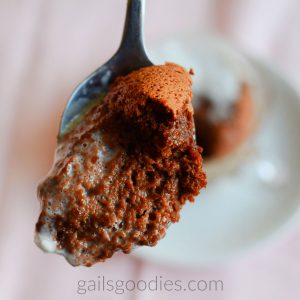 A spoonful of dark chocolate grand marnier souffle is pointed towards the camera. A small amount of the crust is visible on th etop right of the spoonful. Th rest is moist chocolate.
