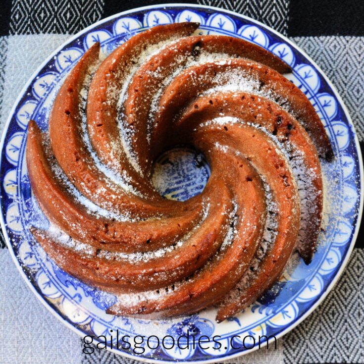 A cappuccino fudge bundt cake viewed from the top. The caramel brown cake was baked in a spiral bundt pan. The cake is dusted with powdered sugar.